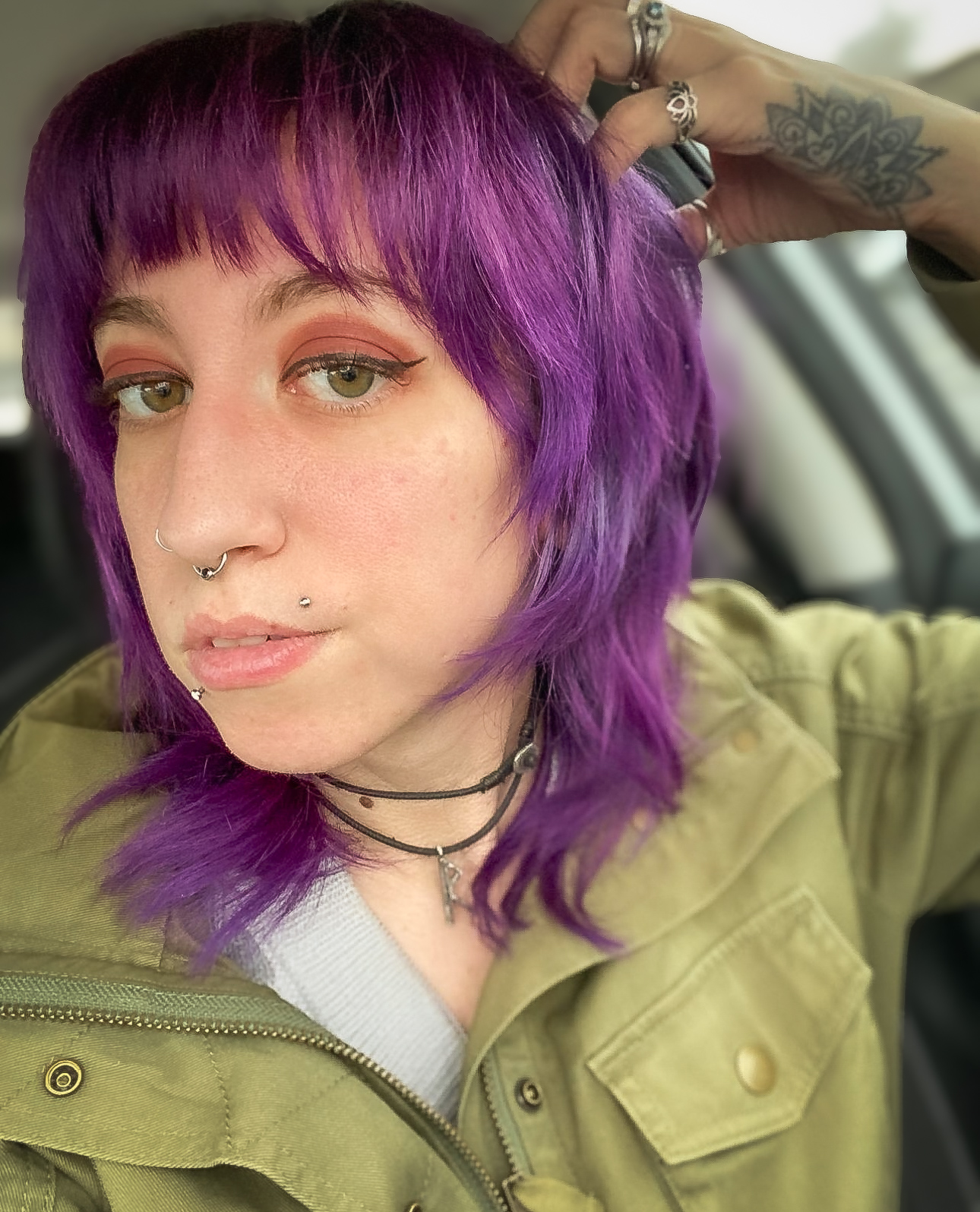 A selfie of Sara in her car. She is sporting purple hair in this photo.